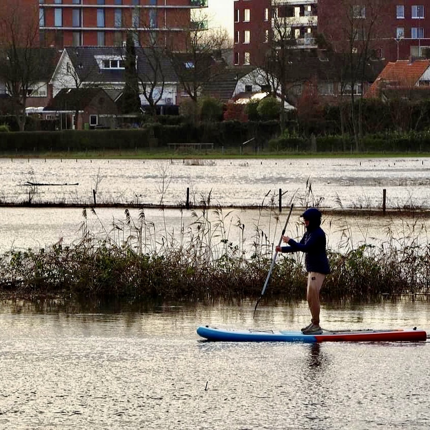 Joris paddle boarding on calm water.
